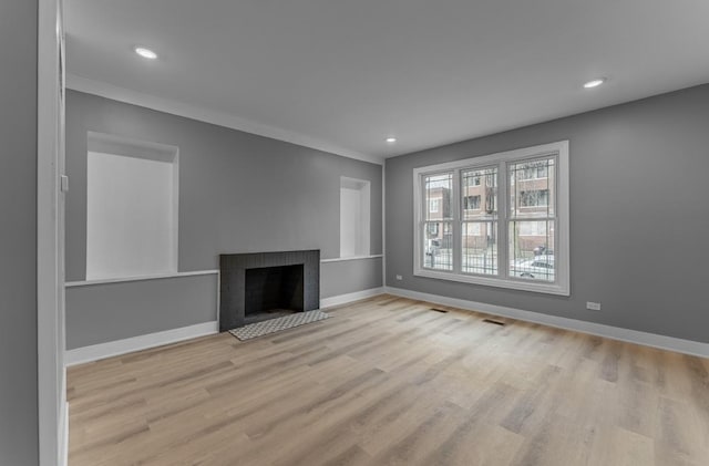 unfurnished living room featuring a fireplace and light hardwood / wood-style floors