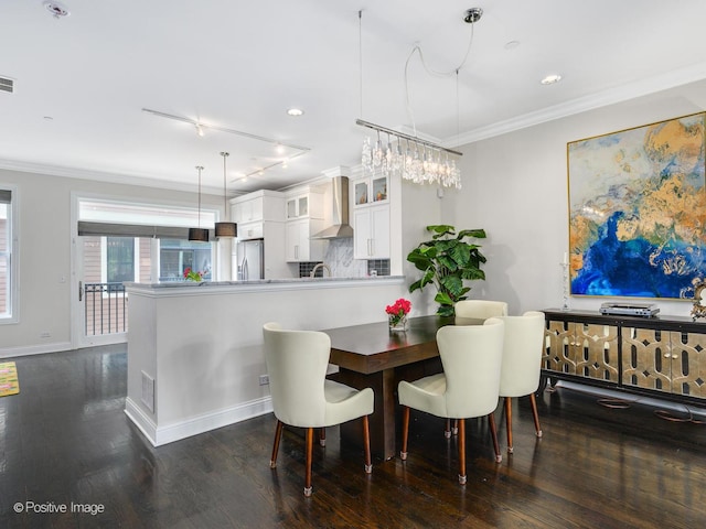 dining area with track lighting, ornamental molding, and dark hardwood / wood-style floors