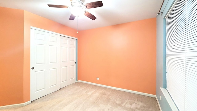 unfurnished bedroom featuring ceiling fan, light colored carpet, and a closet