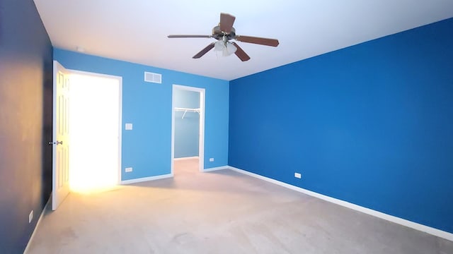 unfurnished bedroom featuring ceiling fan, carpet, a closet, and a walk in closet