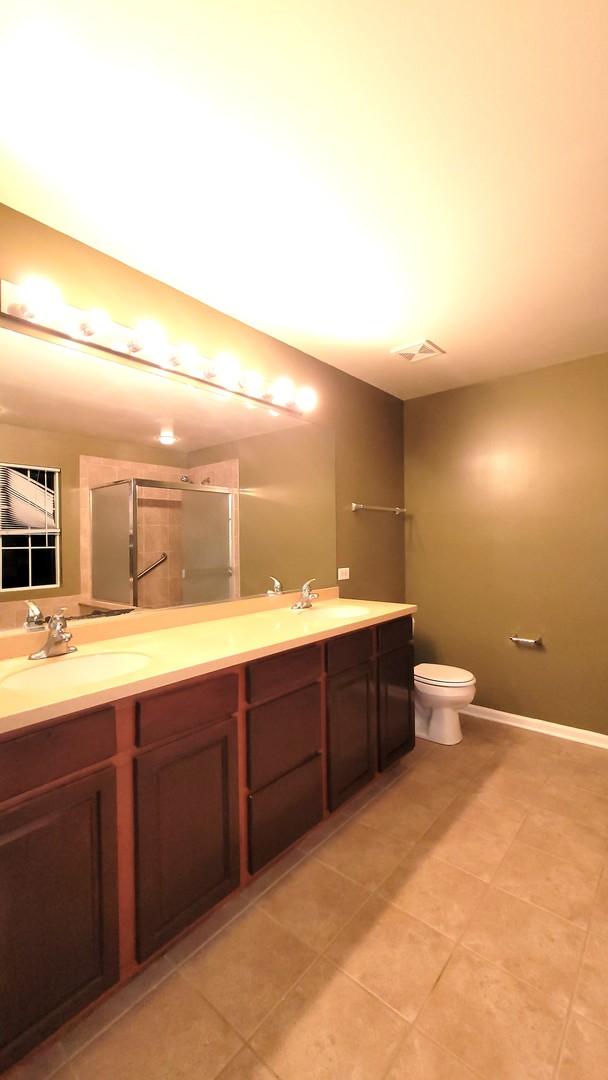 bathroom featuring vanity, toilet, a shower with shower door, and tile patterned flooring