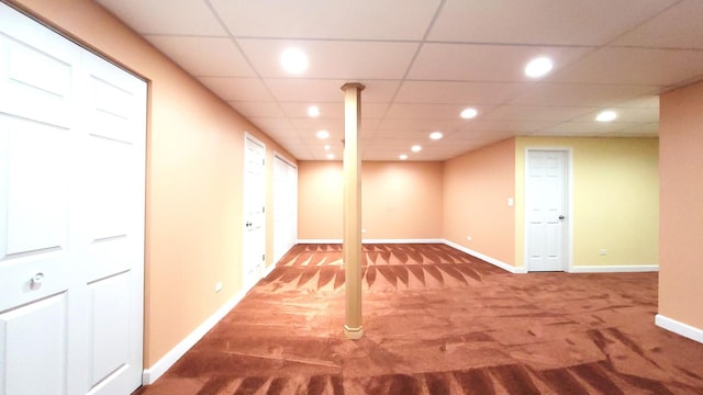 basement with a paneled ceiling and carpet