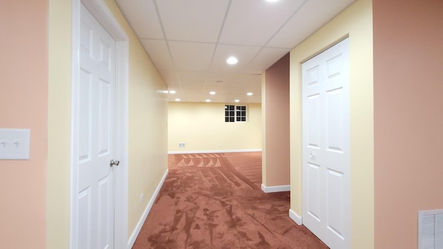 corridor with a drop ceiling and carpet flooring