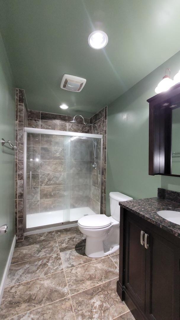 bathroom featuring vanity, toilet, and a shower with shower door