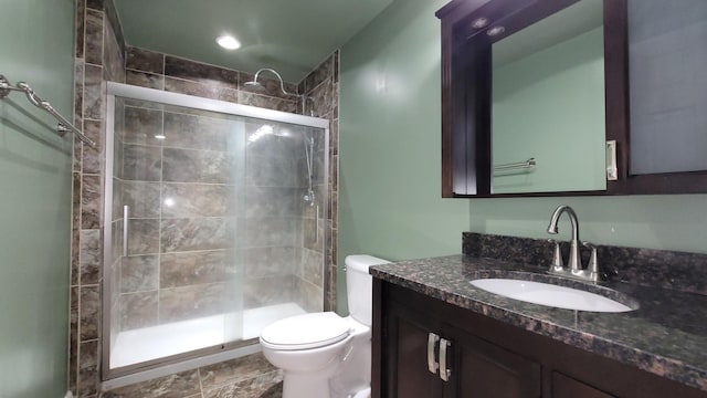 bathroom featuring a shower with door, vanity, and toilet