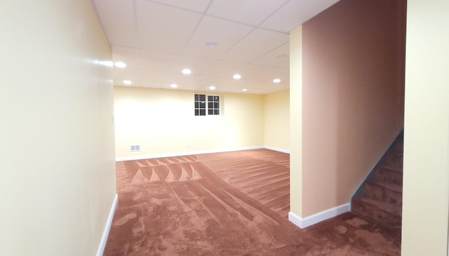 basement with a paneled ceiling and carpet