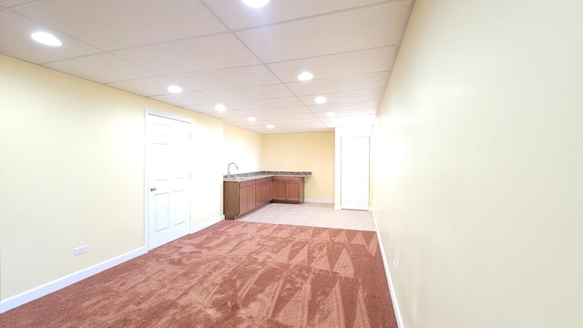 interior space featuring sink, a paneled ceiling, and light colored carpet