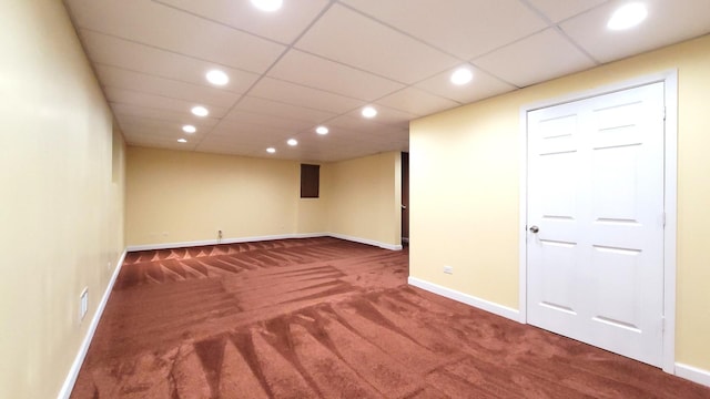 basement with a paneled ceiling and carpet