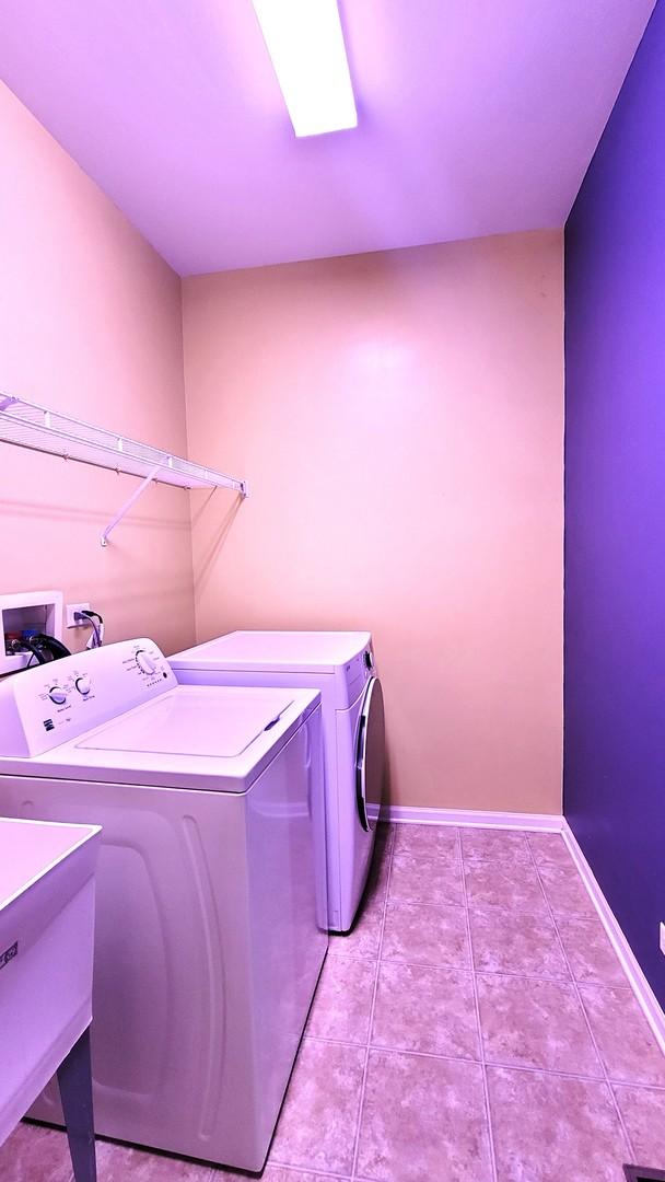 laundry room featuring sink, light tile patterned floors, and washer and clothes dryer