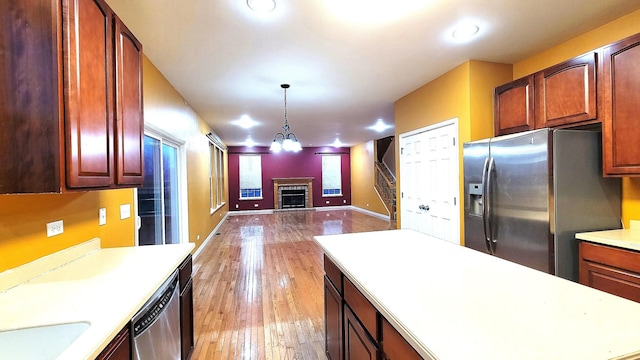 kitchen with stainless steel appliances, sink, hanging light fixtures, and light wood-type flooring