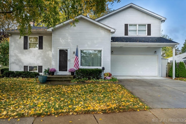 tri-level home with an attached garage, driveway, and entry steps