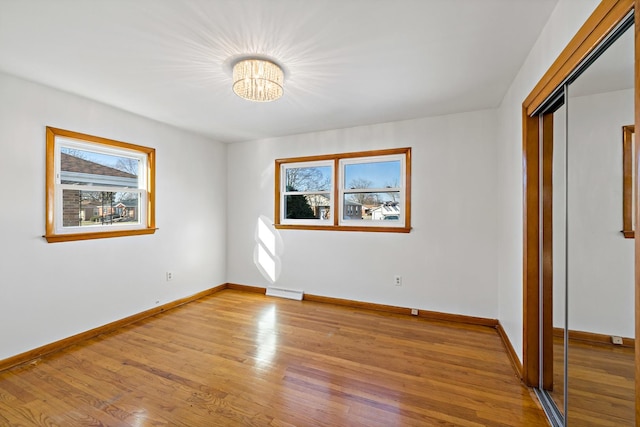 unfurnished bedroom with light hardwood / wood-style floors, a closet, and a notable chandelier