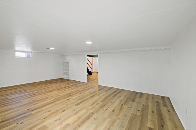 basement featuring wooden walls and light hardwood / wood-style flooring