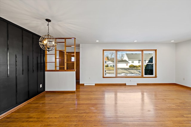 unfurnished living room with a notable chandelier and light hardwood / wood-style flooring