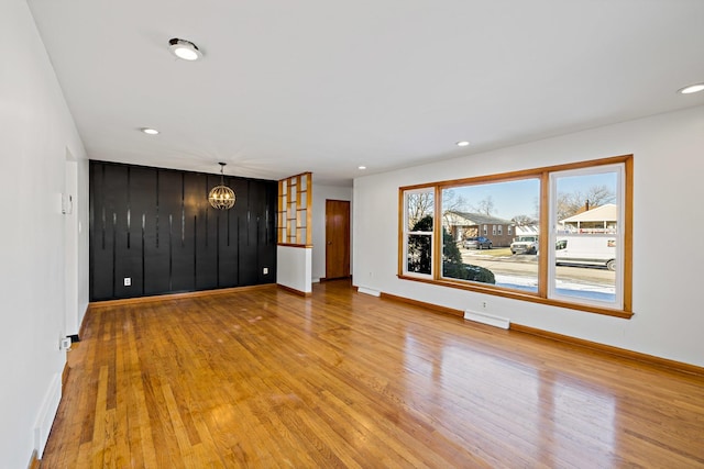 unfurnished living room featuring wood-type flooring and a chandelier