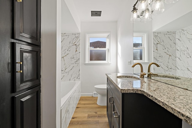 bathroom featuring a tub, wood-type flooring, toilet, and vanity