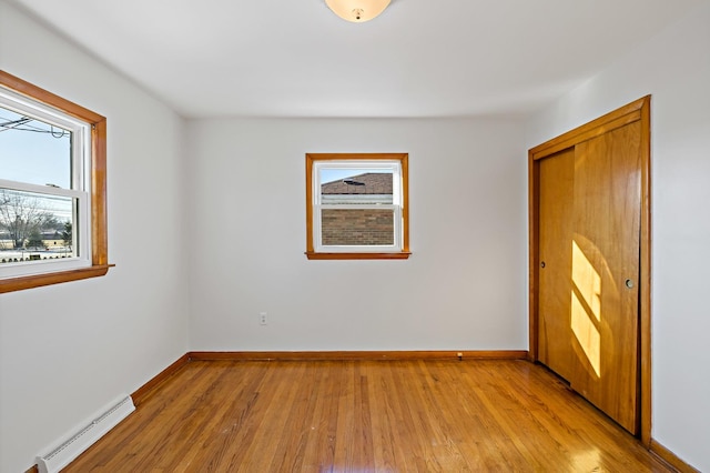 unfurnished room featuring a baseboard heating unit and light hardwood / wood-style flooring