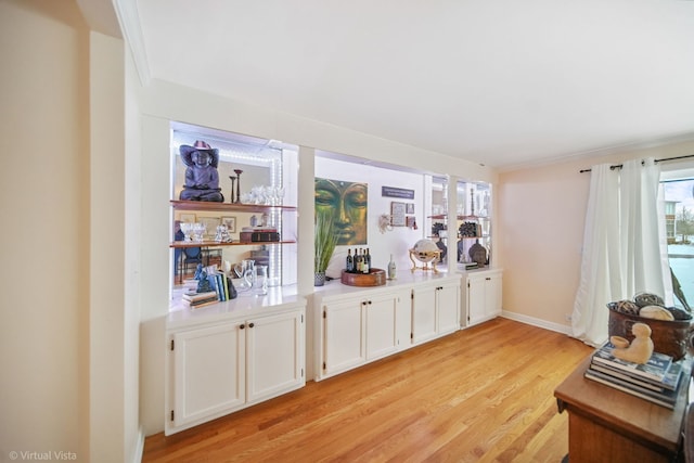 bar featuring ornamental molding, white cabinets, and light hardwood / wood-style flooring