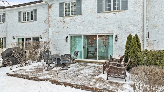 snow covered back of property with a patio area