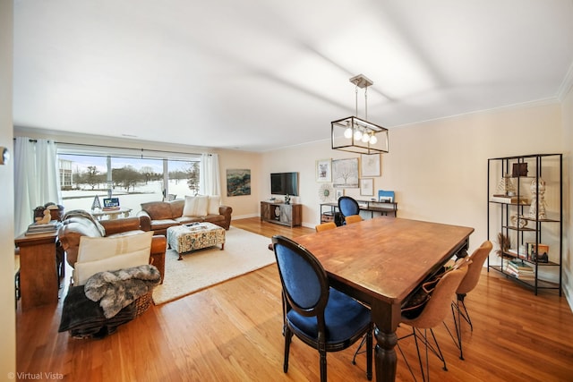 dining area featuring crown molding, wood-type flooring, and a chandelier