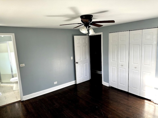 unfurnished bedroom featuring ceiling fan, connected bathroom, dark hardwood / wood-style floors, and a closet