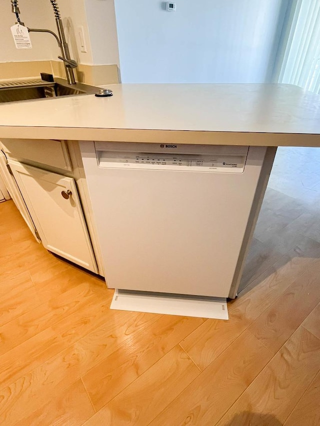 kitchen with dishwashing machine, light wood-type flooring, and sink