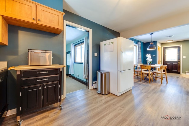 kitchen featuring pendant lighting, light brown cabinets, white refrigerator, light wood-type flooring, and dark brown cabinets