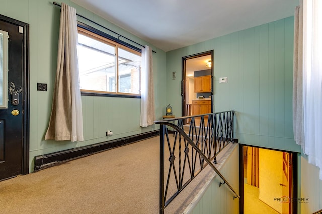 hallway featuring light colored carpet and baseboard heating