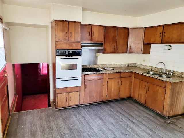 kitchen with black gas stovetop, tasteful backsplash, sink, white oven, and dark wood-type flooring