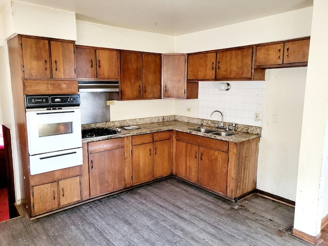 kitchen featuring decorative backsplash, dark hardwood / wood-style flooring, black gas stovetop, oven, and sink