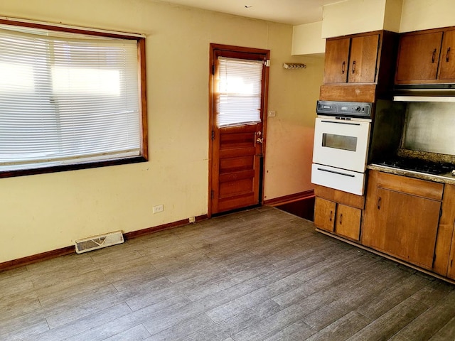 kitchen with hardwood / wood-style flooring, white oven, black electric stovetop, and exhaust hood