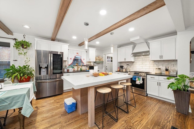 kitchen featuring decorative light fixtures, premium range hood, white cabinets, and stainless steel appliances