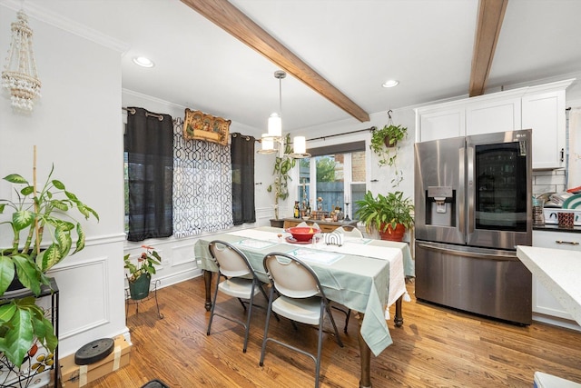 dining area with light wood-type flooring, ornamental molding, beam ceiling, and a chandelier