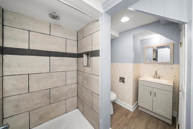 bathroom with toilet, a tile shower, hardwood / wood-style floors, and vanity