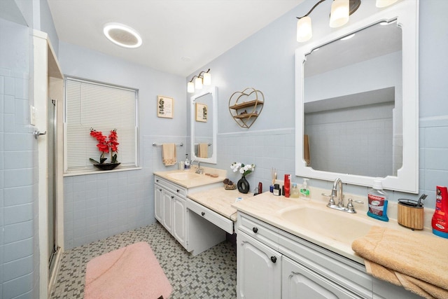 bathroom featuring a shower with shower door, vanity, and tile walls