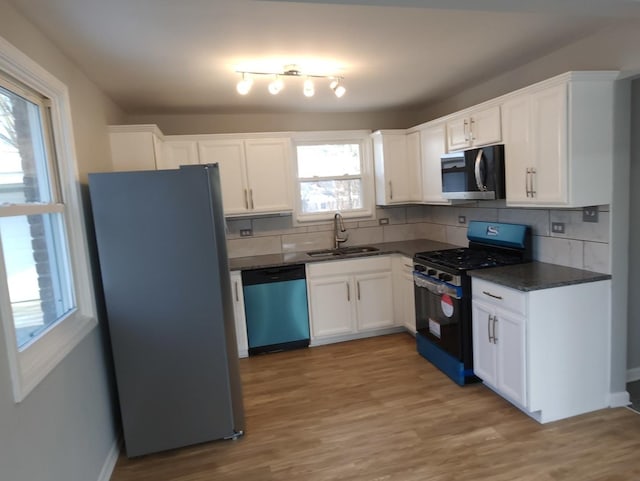 kitchen featuring white cabinets, appliances with stainless steel finishes, decorative backsplash, sink, and light hardwood / wood-style flooring