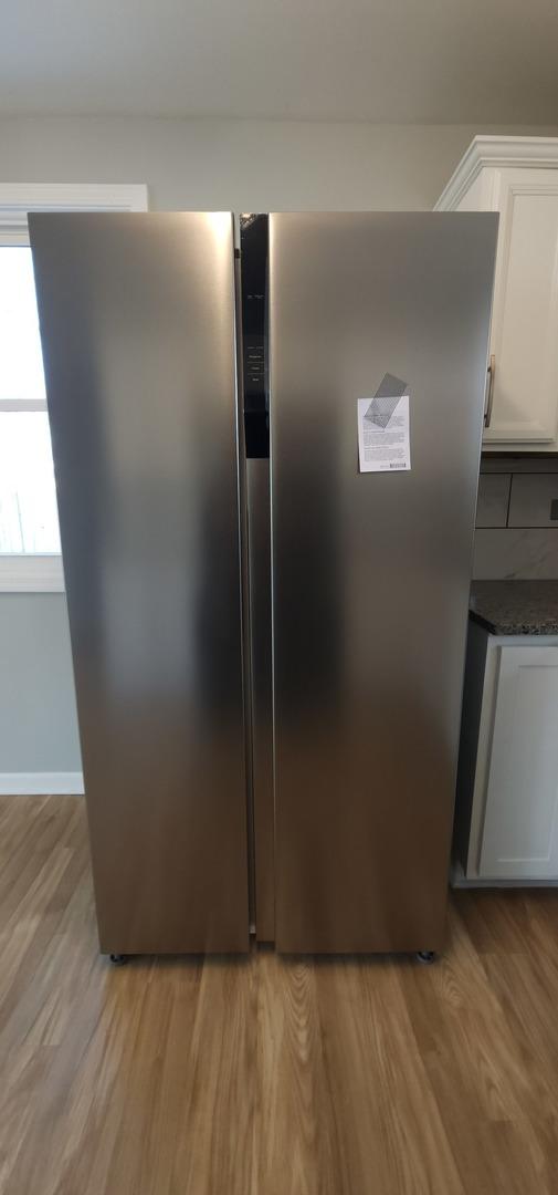 interior details featuring white cabinetry, dark stone countertops, light hardwood / wood-style floors, and stainless steel refrigerator