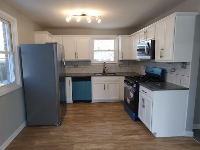 kitchen with hardwood / wood-style flooring, stainless steel appliances, tasteful backsplash, white cabinets, and sink