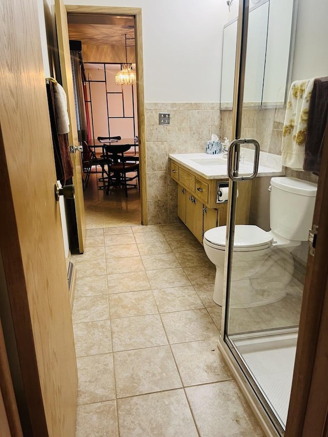 bathroom with tile walls, tile patterned flooring, an enclosed shower, vanity, and toilet