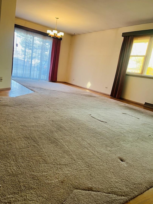 carpeted spare room with an inviting chandelier