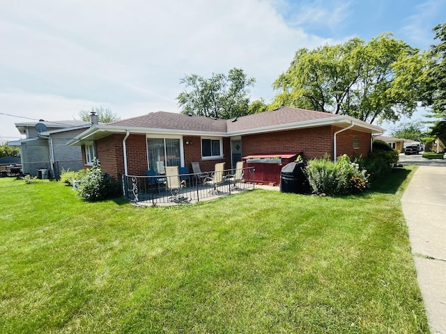 back of property featuring a patio, a jacuzzi, and a lawn