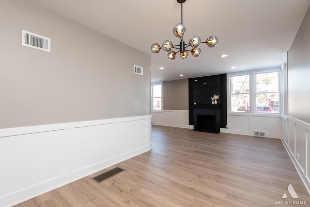 unfurnished living room featuring hardwood / wood-style floors, a healthy amount of sunlight, a chandelier, and a large fireplace