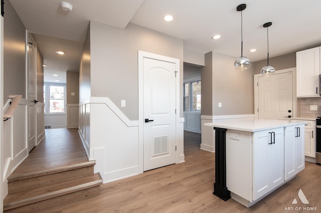 kitchen with white cabinetry, hanging light fixtures, a center island, and light wood-type flooring