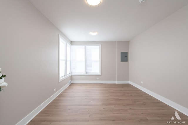 unfurnished room featuring electric panel and light hardwood / wood-style flooring