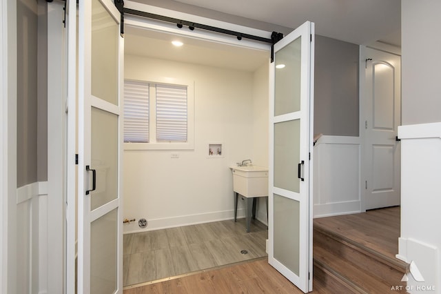 laundry room featuring washer hookup, a barn door, and hardwood / wood-style floors