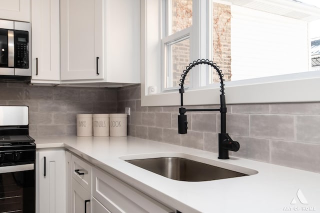 kitchen featuring sink, white cabinets, tasteful backsplash, and range with gas stovetop