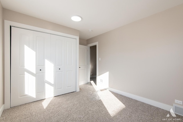 unfurnished bedroom featuring a closet and light colored carpet