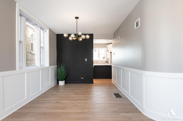 unfurnished dining area with a chandelier and hardwood / wood-style floors