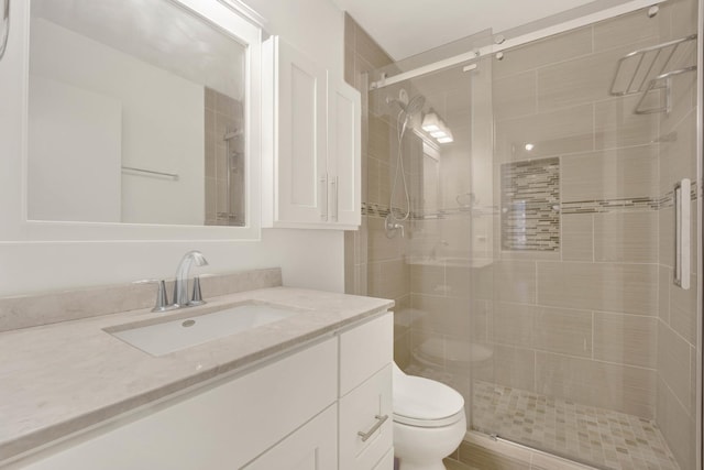 bathroom featuring toilet, an enclosed shower, and vanity