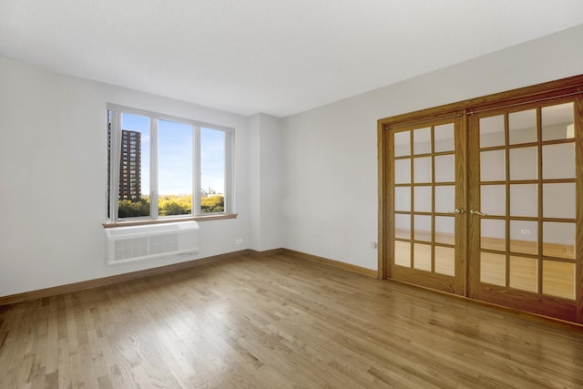 spare room featuring french doors, light hardwood / wood-style flooring, and an AC wall unit